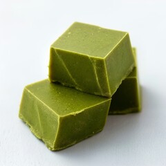 A small pile of three matcha fudge pieces on a white background.