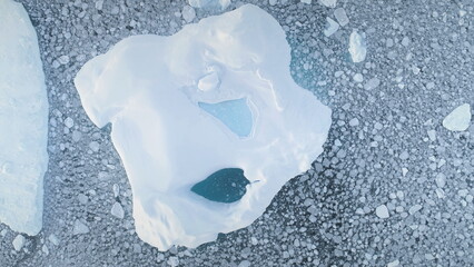 Close-up iceberg. Aerial zoom drone flight. Antarctica landscape. Top down overview of ice mountain. Pieces of frozen ice in polar ocean water. Antarctic continent. Zooming out.