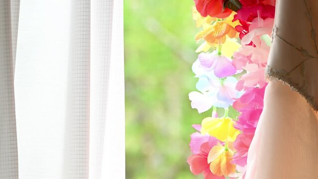 新緑の緑の見える窓際に吊るされたフラワーレイ