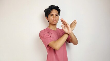 Young Asian man posing with crossed arms on an isolated white background. refusing, saying no,...
