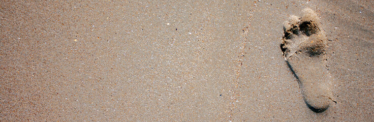 Footprint from the bare foot of a person. Lonely footprint of a man on the wet sand. Sandy beach on a sunny day