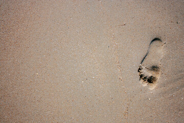 Footprint from the bare foot of a person. Lonely footprint of a man on the wet sand. Sandy beach on...