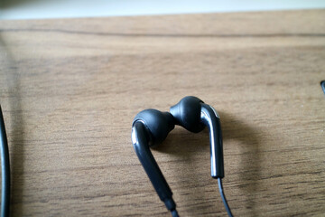 a pair of headsets with cables. black, placed on a table with a wooden motif