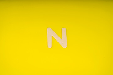 Letter N in wood on yellow background