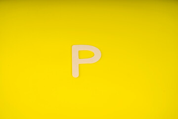 Letter P in wood on yellow background