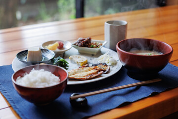 Japanese breakfast includes grilled fish, miso soup, tofu, rice, Japanese pickled vegetables, and Japanese green tea.