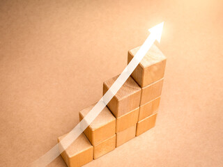 Shining rise up arrow on wooden cube blocks, bar graph chart steps on beige background, profit,...