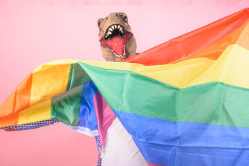 man in T-Rex mask waving a rainbow flag on an isolated background. rights fight concept