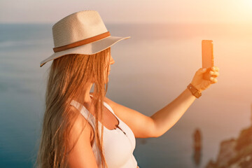 Selfie woman in a hat, white tank top, and shorts captures a selfie shot with her mobile phone...