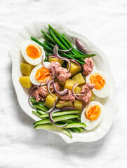 Breakfast, appetizers salads - boiled eggs, potatoes, string beans, red onion, cucumber, canned tuna salad on a light background, top view