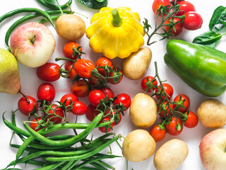 Fresh organic seasonal vegetables and fruits on a white background - cherry tomatoes, potatoes, string beans, squash, pear, apple