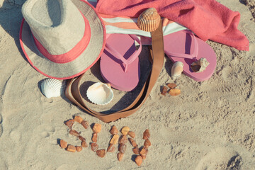 Inscription sun made of amber and accessories for relax on sand. Straw hat, slippers and towel....