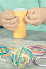Preschooler hands putting rubber bands or erasers on cardboard roll. Development of kids motor skills, coordination logical thinking