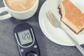 Glucometer with result sugar level, portion of sweet cheesecake and cup of coffee with milk....