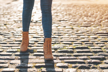 legs of young woman student having a fun time and walking around city at sunset