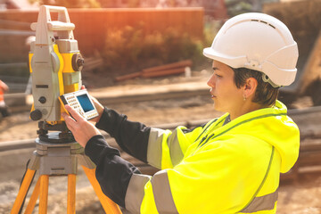 Woman site engineer surveyor working with theodolite total station EDM equipment on  building...