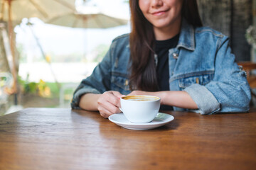 Closeup image of a young woman holding and drinking hot coffee in cafe - 797410080