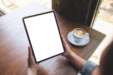 Top view mockup image of a woman holding digital tablet with blank white desktop screen in cafe - 797410677