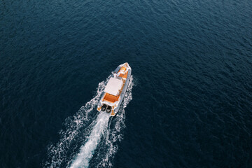 Motor yacht sails on the sea leaving a white foamy trail. Drone