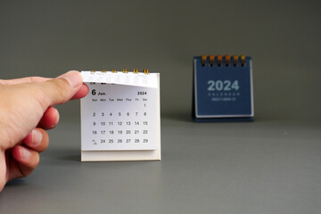 Businessman's hand flips a desk calendar from May 2024 to June 2024.