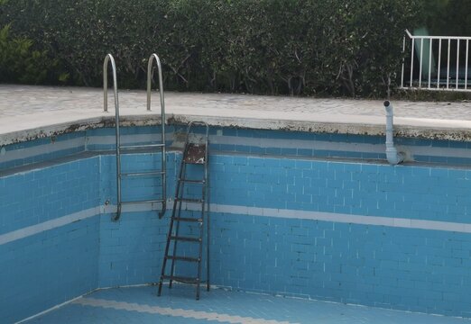 winter maintenance of an empty outdoor swimming pool where the steps are too short and an additional ladder is used