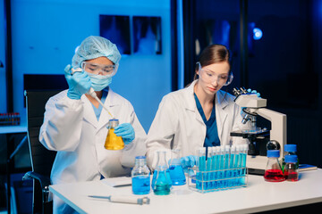 Young scientists conducting research investigations in a medical laboratory, a researcher in the foreground is using a microscope in laboratory