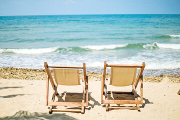 Fototapeta premium Seaside picnic chairs on an island with white beaches and bright blue waters for vacationers looking to relax.