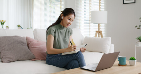 Reskill upskill for young adult talent workforce remote work at home hybrid workplace. Asia woman happy smile sit at sofa couch learn online study MBA video call share plan idea write note on tablet.