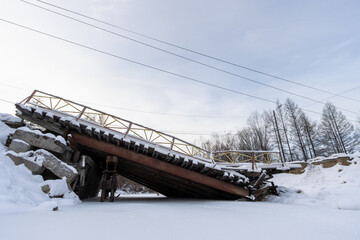 View of the collapsed road bridge. Collapsed bridge over a small river. Fallen damaged bridge. Consequences of an emergency. Cold winter weather. A lot of snow. - 797454028