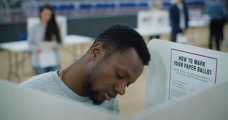 African American male voter comes to voting booth. American citizens come to vote in polling station. Political races of US presidential candidates. National Election Day in United States. Close up. - obrazy, fototapety, plakaty