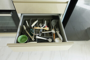 Close up of messy kitchen utensil drawer.
