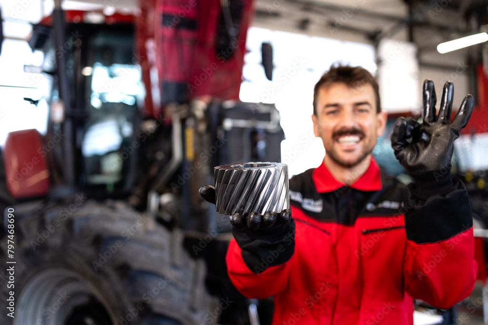 Wall mural Mechanic holding spare parts for tractor service.