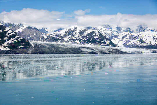 Spiegeling in het water met ijsschotsen met uitzicht op een gletsjer en met sneeuw bedekte bergen in Alaska.