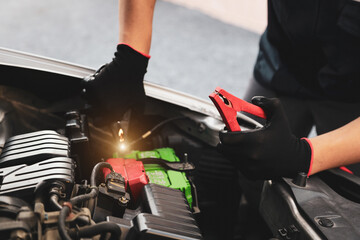 Hand car mechanic holding car booster cables for jump start car for empty battery dead and low...