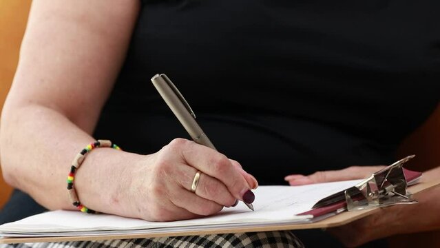 close-up of senior woman's hands writing with pen