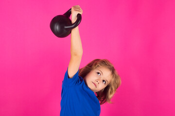 Kid with kettlebell in studio on red pink background. Kid raising a kettlebell. Cute child training with dumbbells. Kids fitness. Kid boy exercising with dumbbells. Healthy kids.