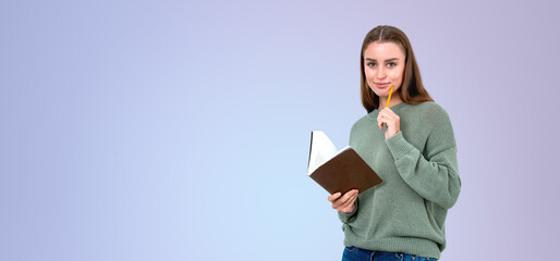 A thoughtful woman holding a book and a pencil, wearing a green