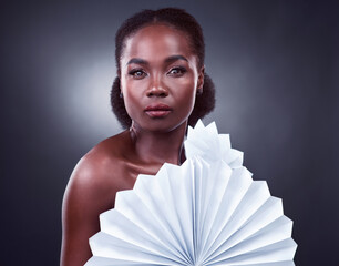 Black woman, portrait and beauty origami in studio, cosmetics and oriental fans on dark background....