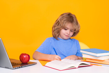 Child writing lesson. Child from elementary school with book isolated on yellow background. Little student, clever nerd pupil ready to study. First time to school. Concept of education and learning.