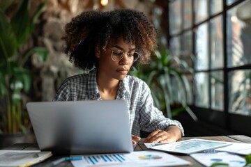 African analyst working on hybrid laptop with data spreadsheet