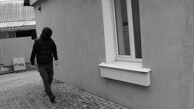 Thief or burglar in the house filmed on a CCTV camera sneaks along the wall