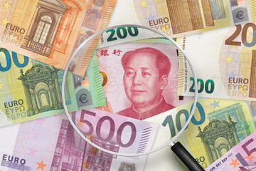 Chinese yuan and Euros banknotes. EU and China trade war . View through magnifying glass
