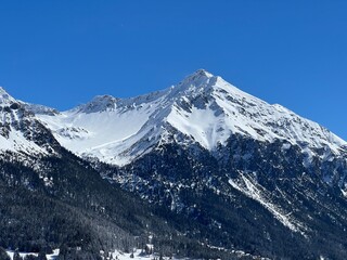 Beautiful sunlight and snow-capped alpine peaks above the Swiss tourist sports-recreational winter...