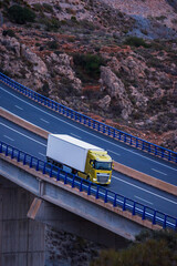 Truck with refrigerated trailer driving on a viaduct, elevated view.