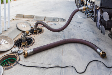 Hoses in a fuel discharge, connected from the tanker truck to the gas station manholes, discharging...