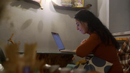 Focused entrepreneur at laptop in cozy cafe engages in remote work, typing, analyzing data. Casual business in public space, modern freelance job lifestyle. Female pro multitasks, uses tech. - Powered by Adobe