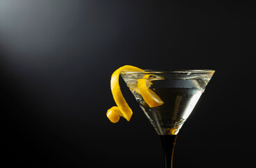 Glass of classic dry martini cocktail with green olives on a black background.