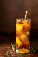 Cocktail with ice, rosemary and lemon slices on the old brown table.