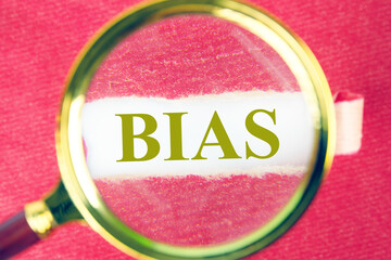 Concept of facts and biases. A word BIAS through a magnifying glass under a piece of torn paper