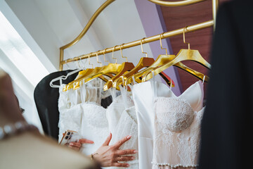 Woman examines wedding dresses on clothes hangers for event